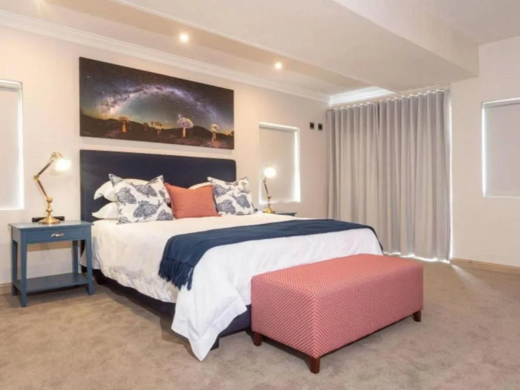 Modern bedroom with navy headboard, white bedding, and coral accents throughout