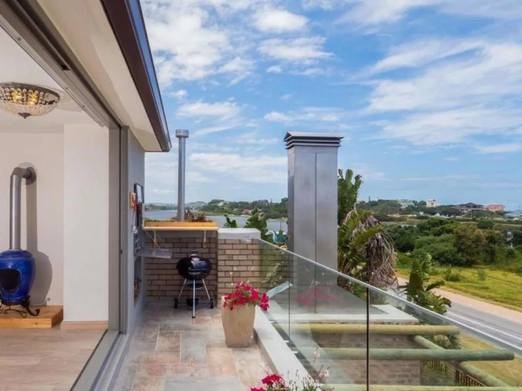 Spacious outdoor deck with braai, water views, and lush landscaping