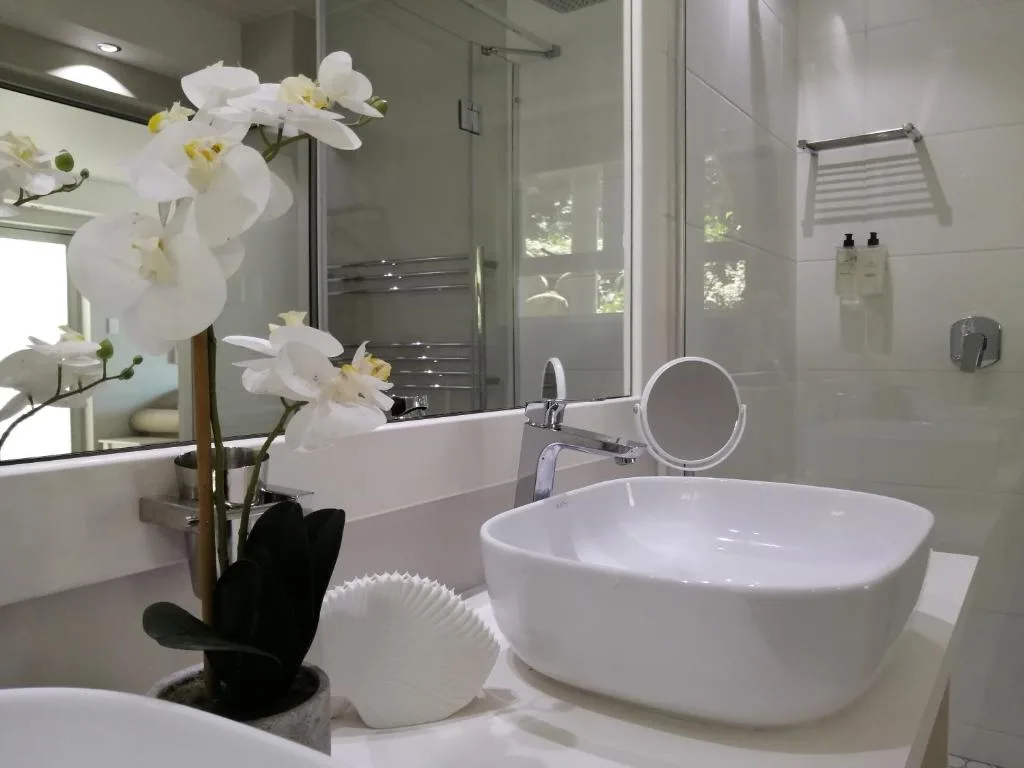 Modern bathroom with white vessel sink, orchid flowers, and glass shower enclosure
