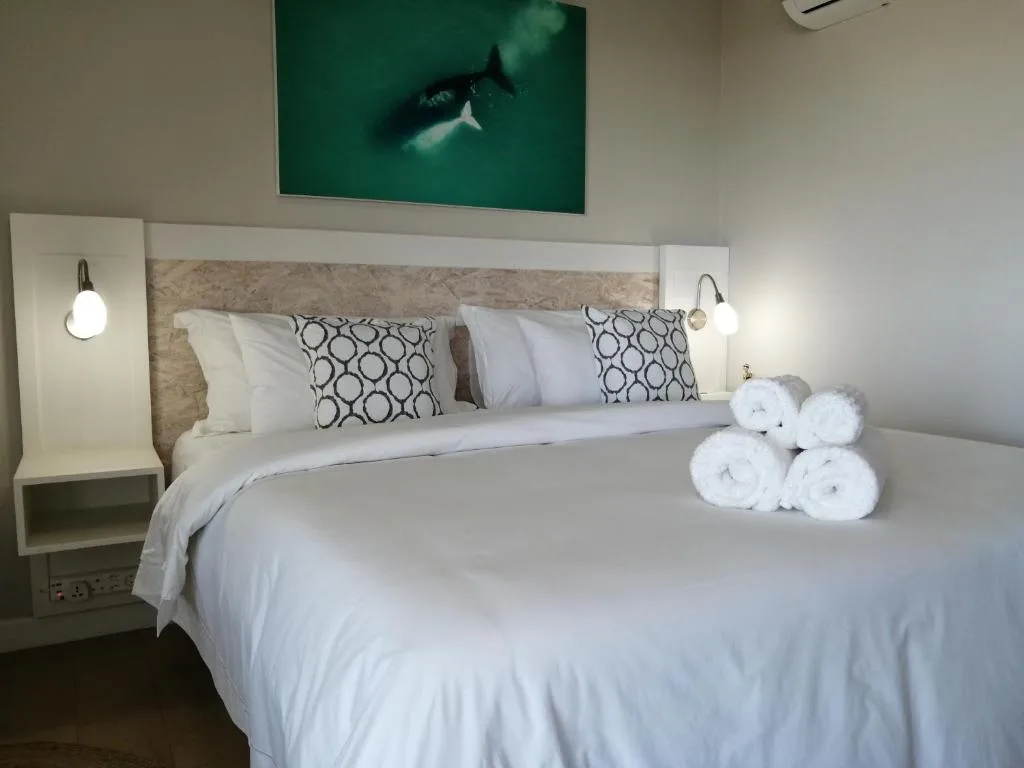 Modern bedroom with white bedding, geometric pillows, and fresh towels