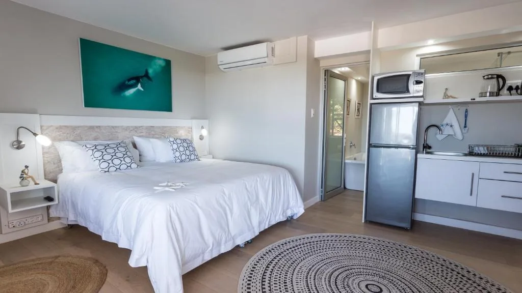 Modern bedroom with queen bed, kitchenette, and whale artwork above headboard