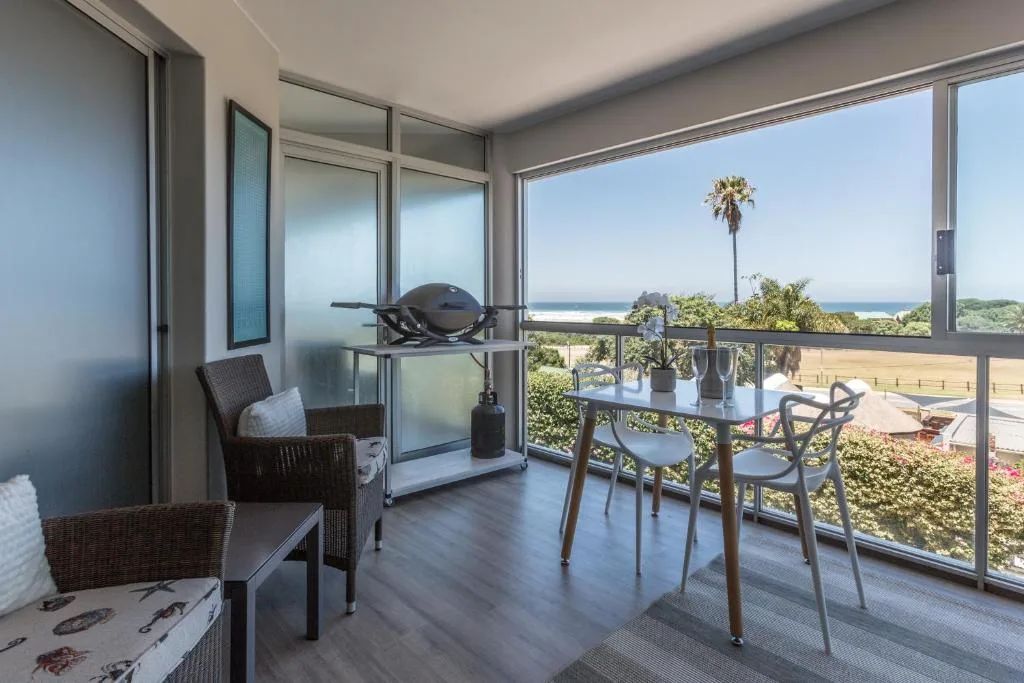 Covered outdoor deck with dining table and ocean view beyond