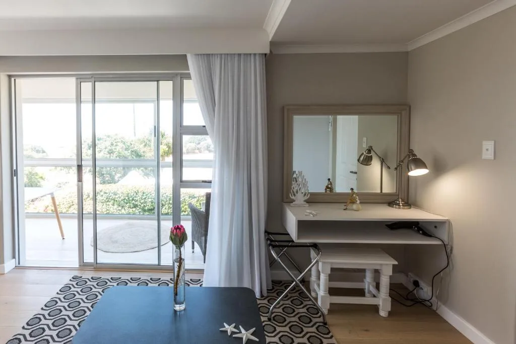 Modern vanity desk with mirror, lamp, and stool in bright bedroom