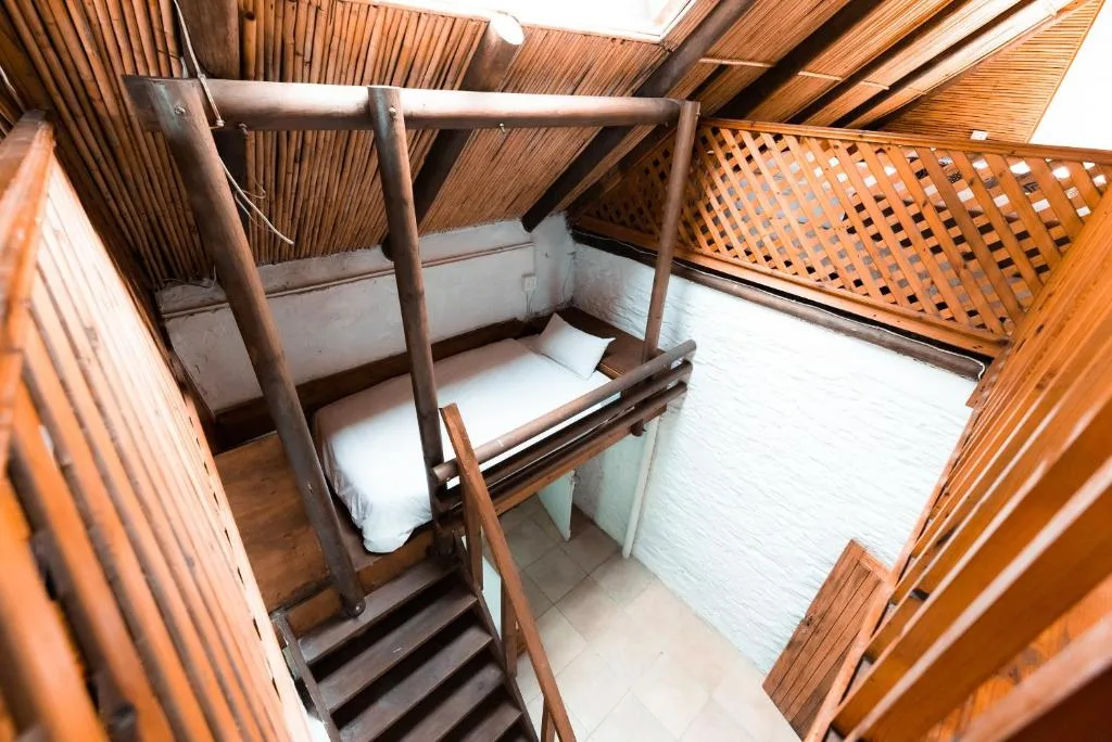 Wooden four-poster bed with white linens in rustic bedroom space