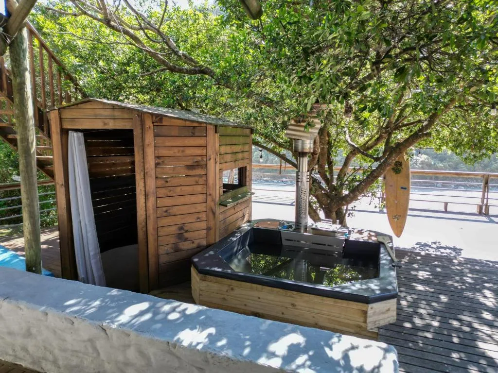 Wooden deck with hot tub, braai area, and mature trees overhead