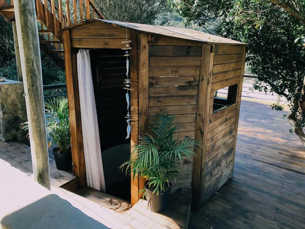 Wooden outdoor shower structure with curtain and potted plants on deck