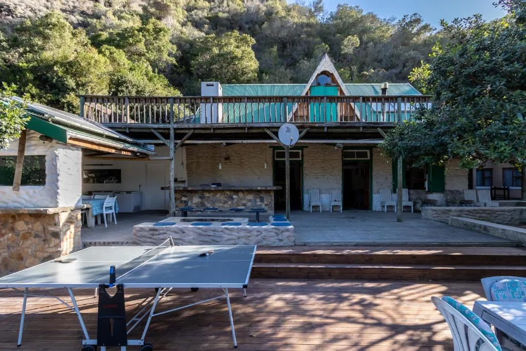 Main house facade with elevated deck and turquoise railings surrounded by trees