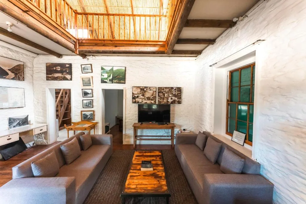 Spacious living room with brown sofas, TV, and wooden ceiling features