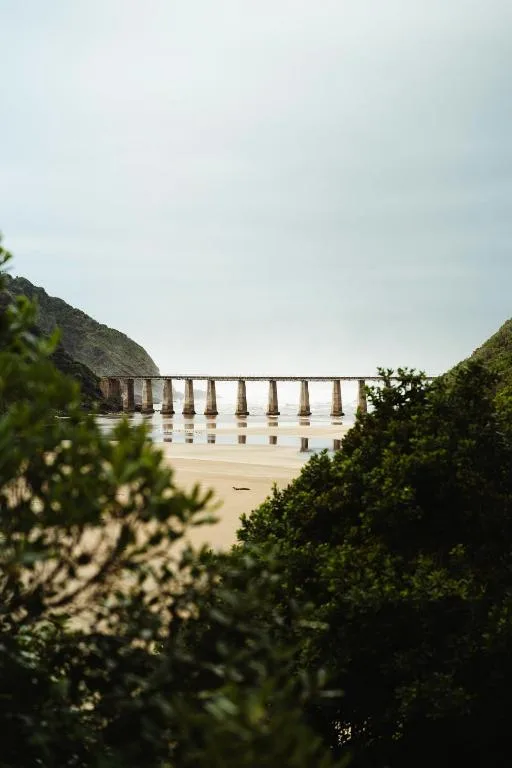 Scenic view of historic bridge spanning across sandy beach and estuary