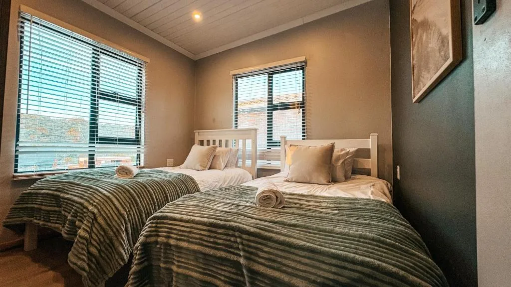 Twin beds with striped bedding in bright room with large windows