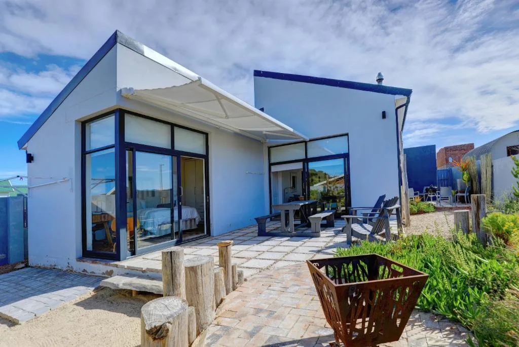 Modern beach house with retractable awning and outdoor seating area