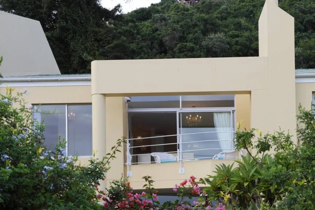 Modern cream-colored apartment facade with large windows and flowering gardens