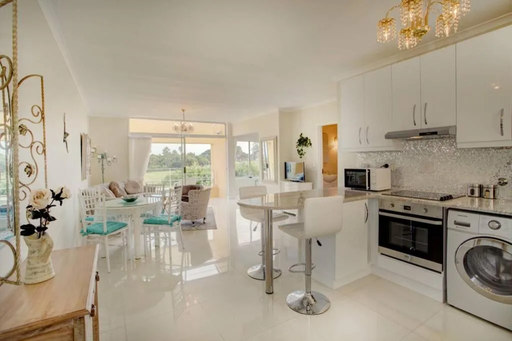 Modern white kitchen with stainless steel appliances and open living area