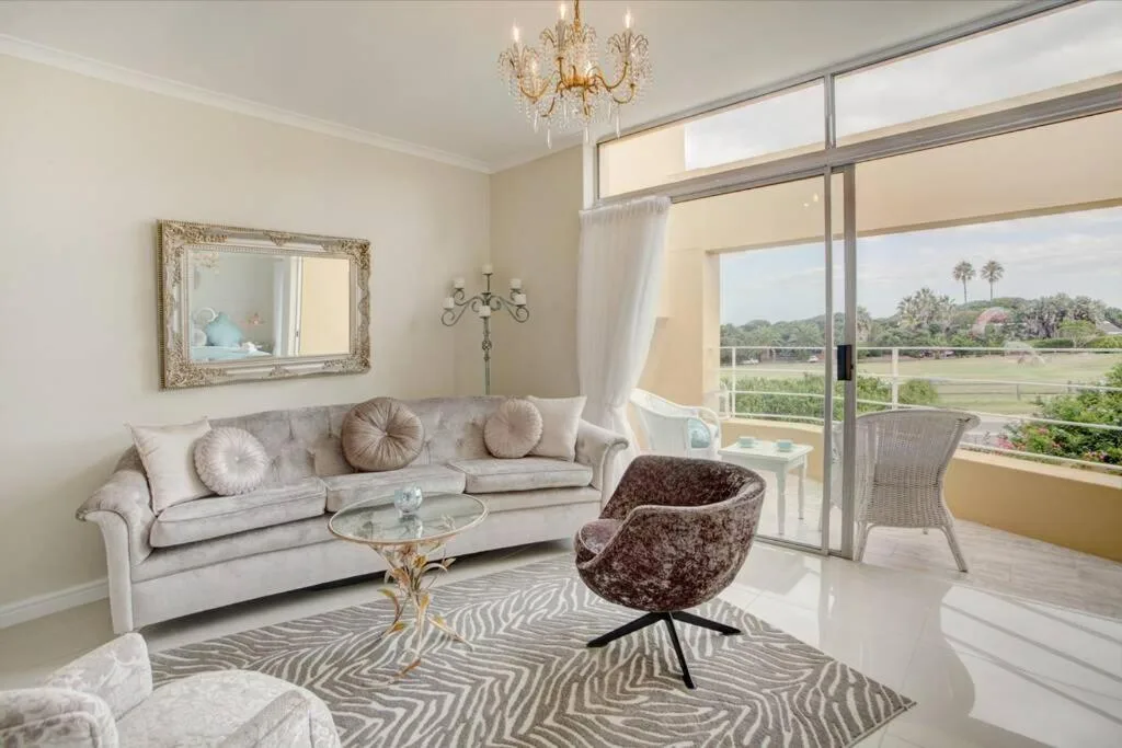 Elegant lounge with cream sofa, patterned rug, and panoramic lagoon views