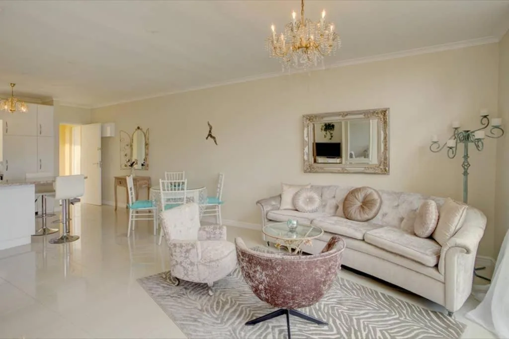 Elegant living room with cream sofa, decorative pillows, and crystal chandelier