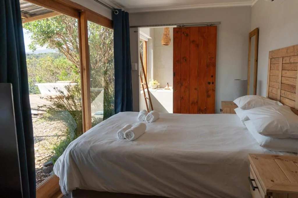 Spacious bedroom with double beds, wooden furniture, and garden view doors