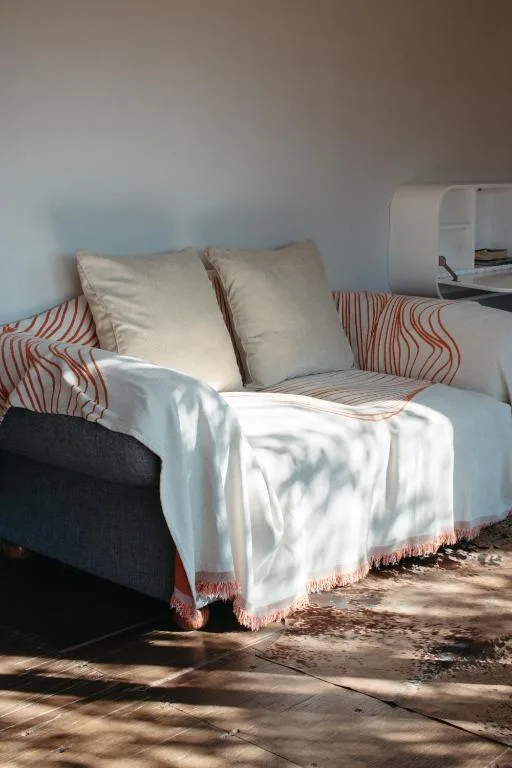 Bright bedroom with striped pillows, white bedding, and afternoon sunlight streaming across the bed