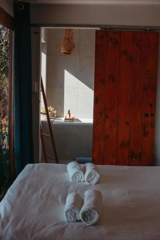 Bed with rolled white towels, red wardrobe doors, bright natural light