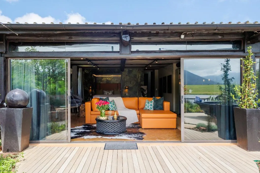 Modern wooden deck with open glass doors revealing orange seating and mountain views