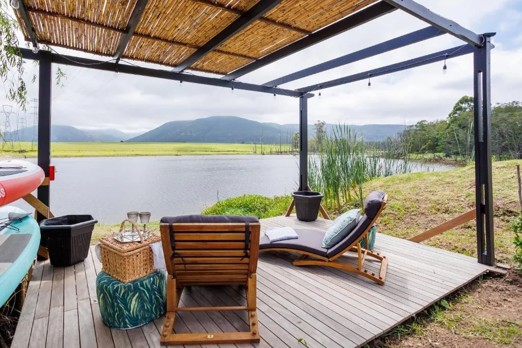 Lakeside deck with pergola, lounge chairs, mountain views beyond