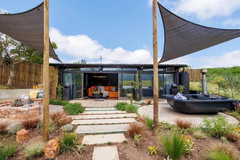 Modern outdoor deck with shade sails, hot tub, and lounge seating area
