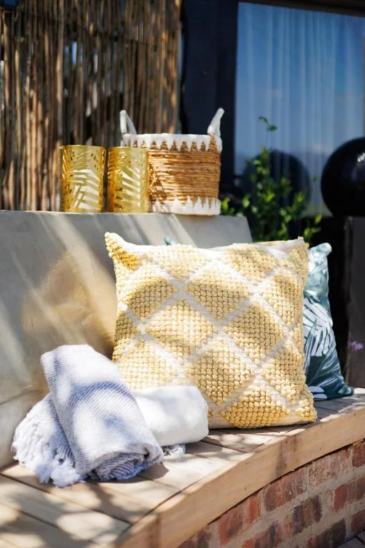 Decorative gold patterned cushion and rolled towels on outdoor seating