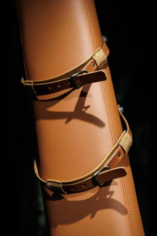 Leather straps with brass buckles on wooden post detail