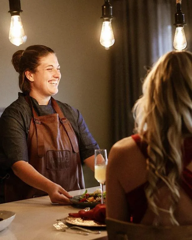 Smiling server presenting fresh salad to guest in elegant dining area