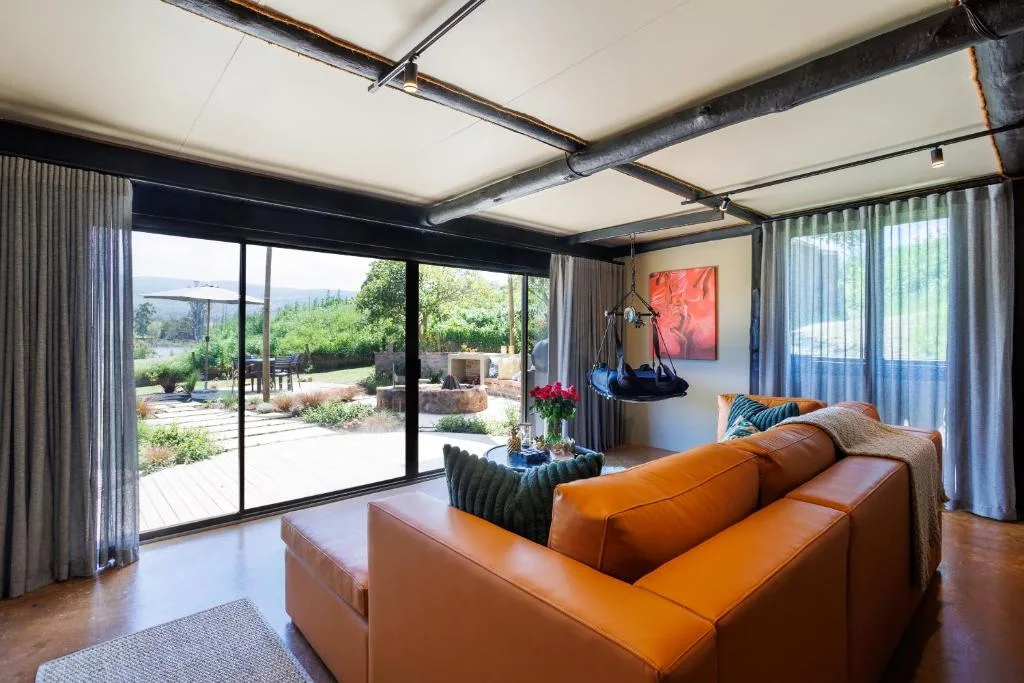 Modern lounge with orange leather sofa overlooking garden through floor-to-ceiling windows