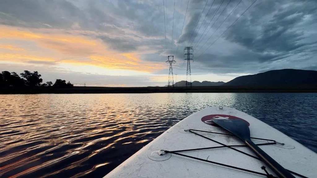 Scenic lagoon sunset with mountains and kayak in foreground