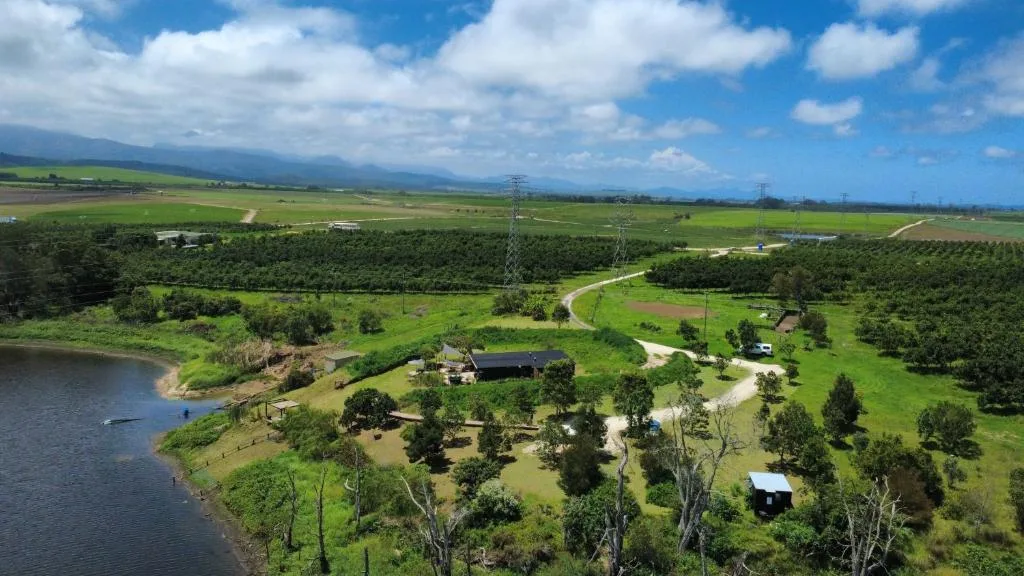 Aerial view of property nestled in lush green valley with river and mountains