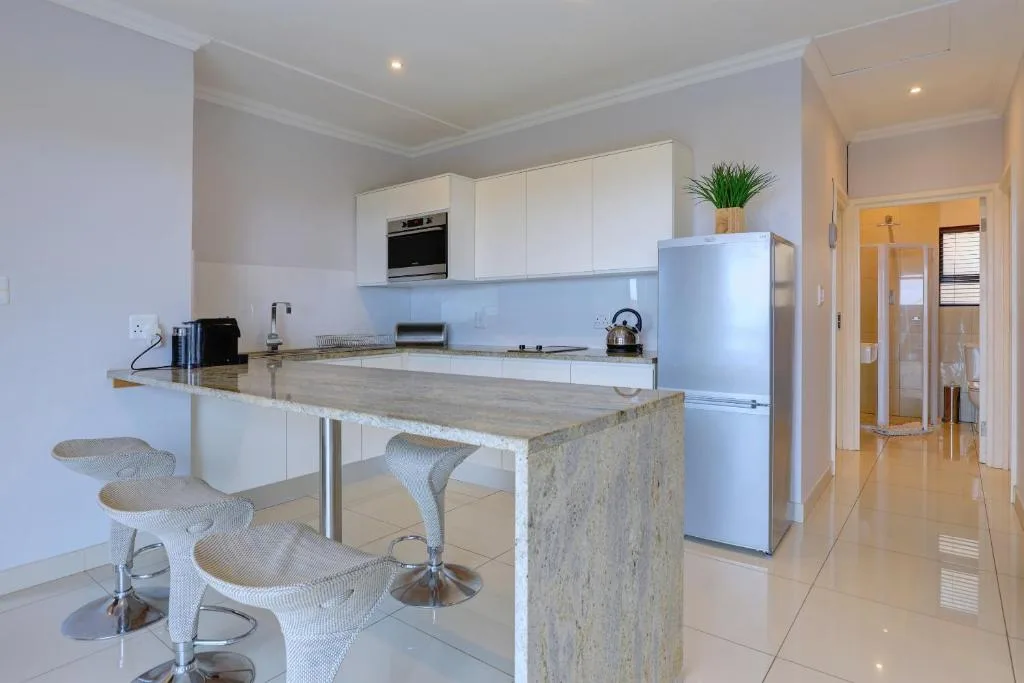 Modern kitchen with white cabinetry, island counter, and bar seating for guests