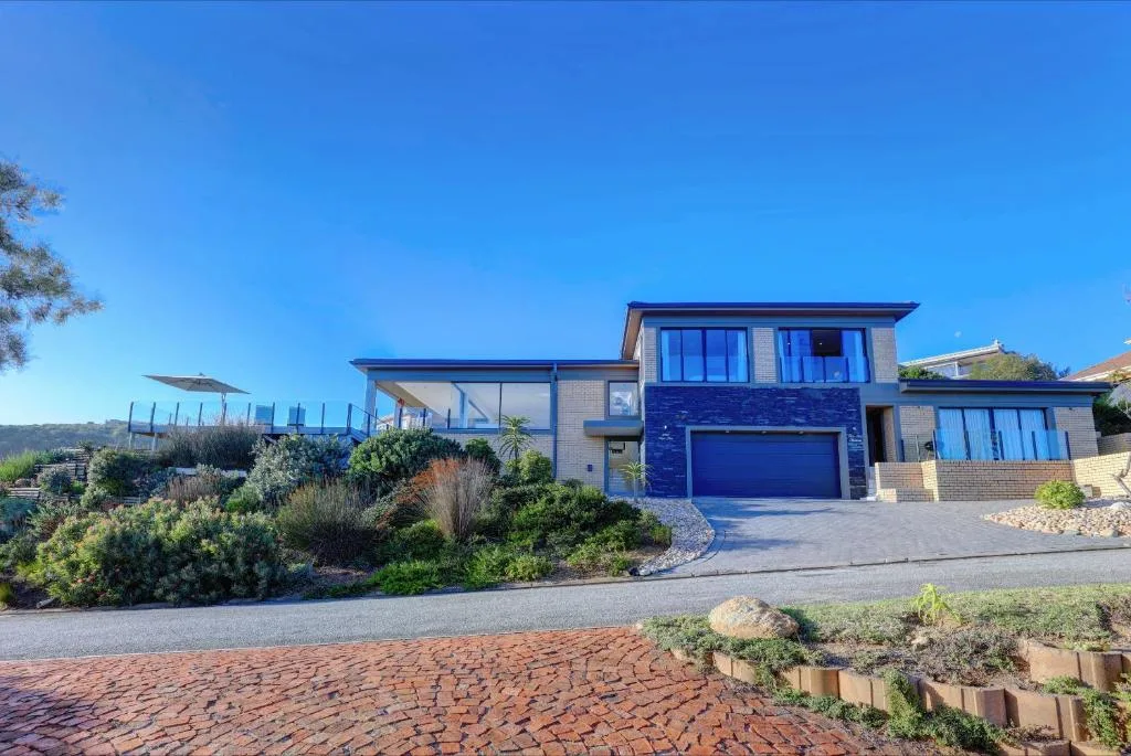 Modern brick house with blue garage door and manicured gardens under clear sky
