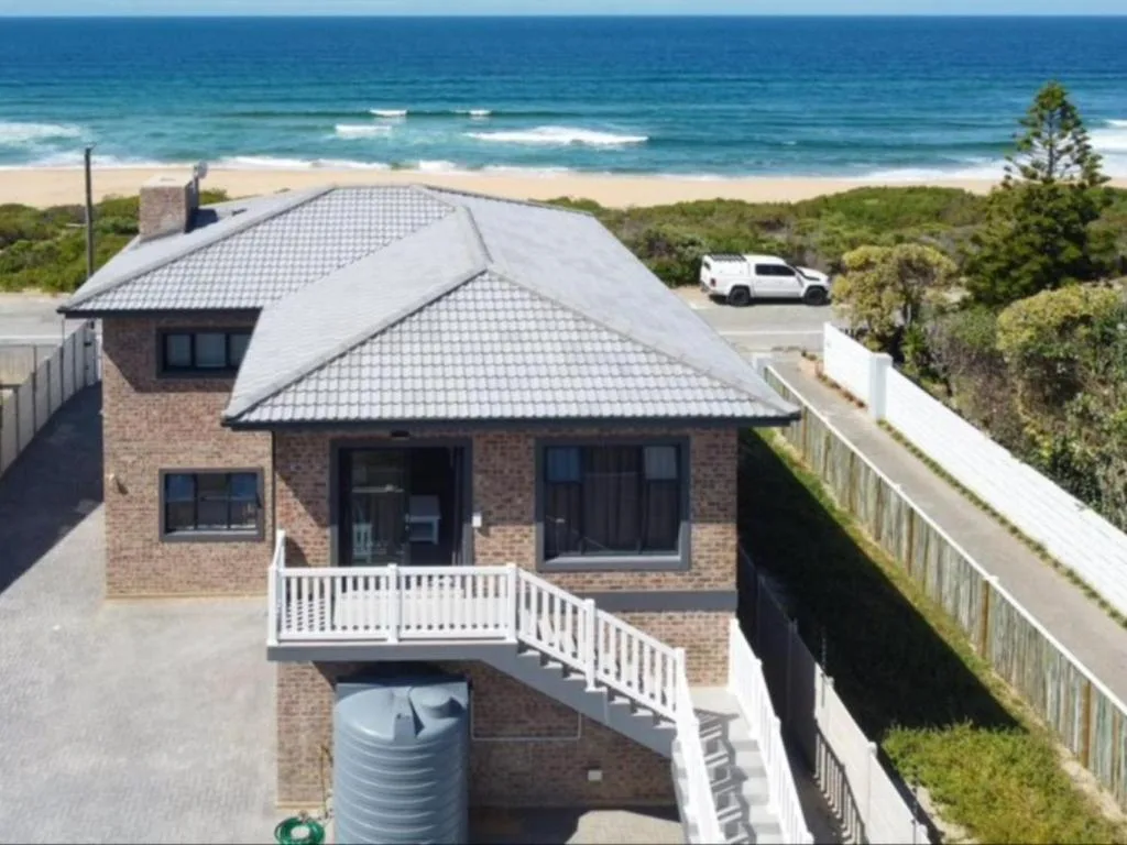 Modern brick beach house with white deck overlooking ocean and sandy beach