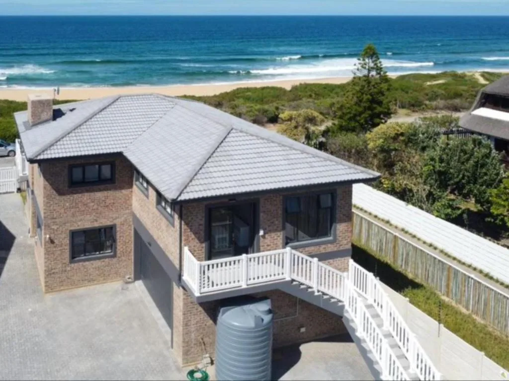 Modern brick house with white deck overlooking beach and ocean waves