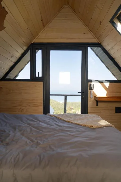 Modern bedroom with bed facing large windows overlooking scenic landscape