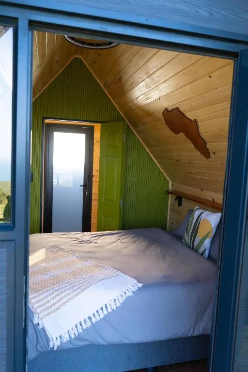 Cozy bedroom with double bed, wooden ceiling, green corrugated walls