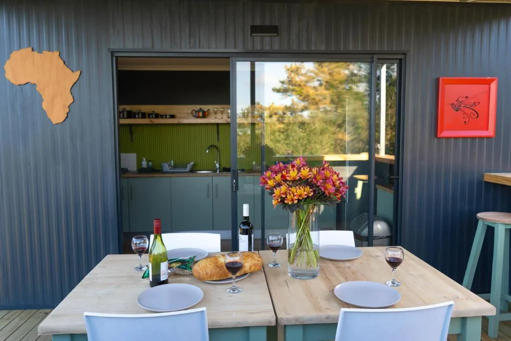 Outdoor dining setup with wooden table, flowers, wine and bread displayed