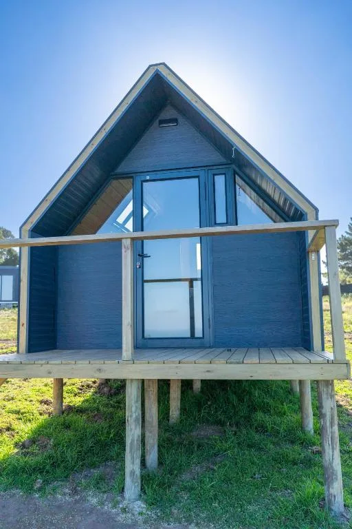 Blue A-frame glamping cabin with wooden deck and pillars