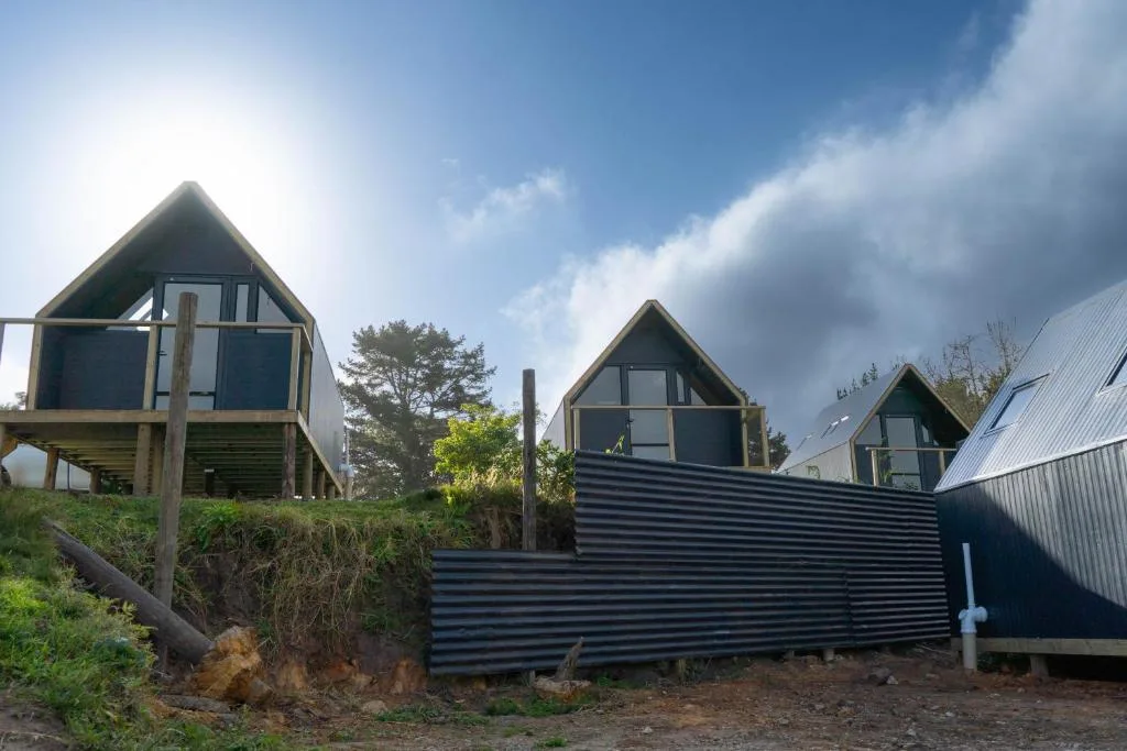 Modern A-frame glamping cabins with dark metal cladding and large windows