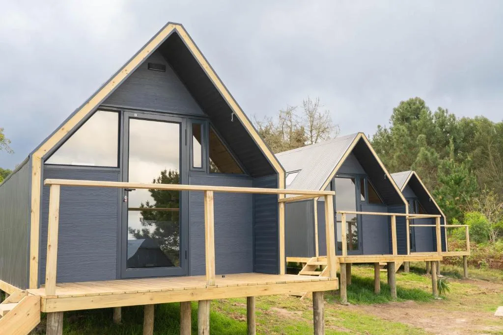 Modern A-frame glamping cabin with wooden deck and natural surroundings