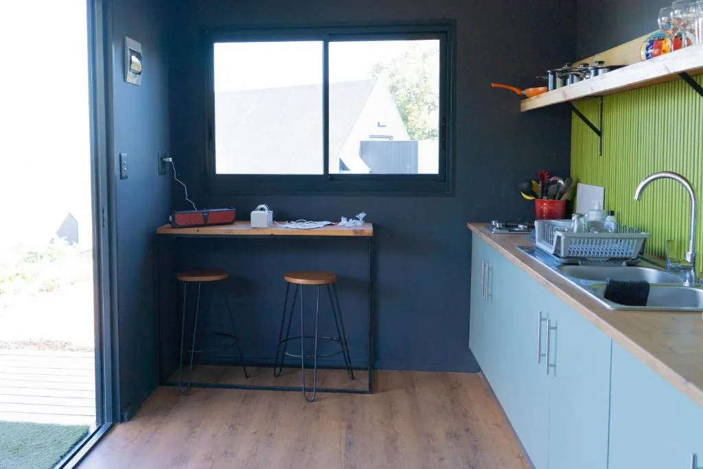 Modern kitchen with blue cabinetry, wooden countertops, sink, and bar seating