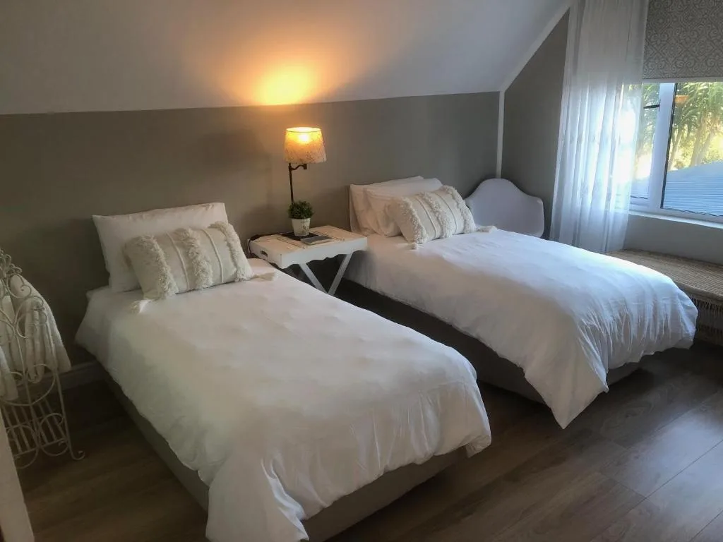 Twin beds with white linens and decorative pillows in bright room