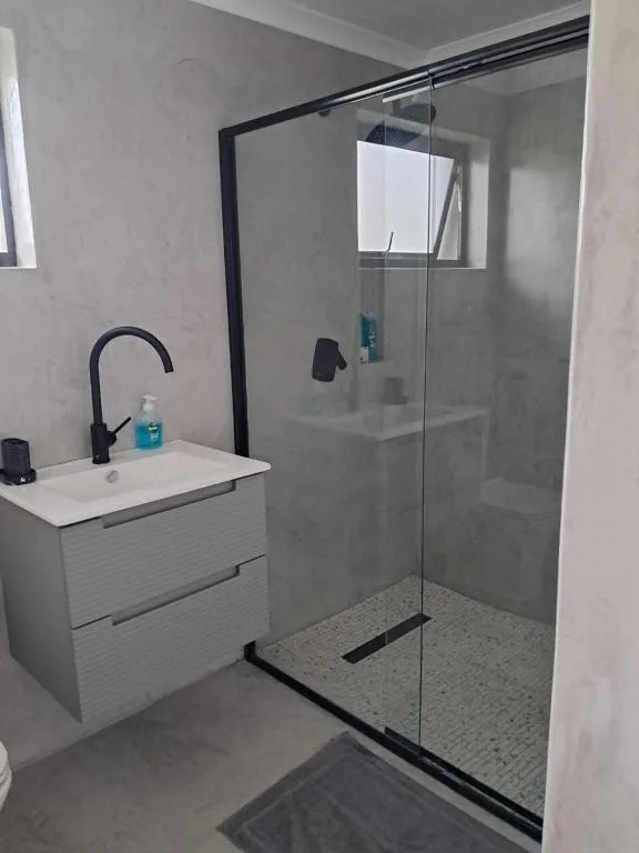 Modern bathroom with white vanity, black faucet, and glass-enclosed shower area