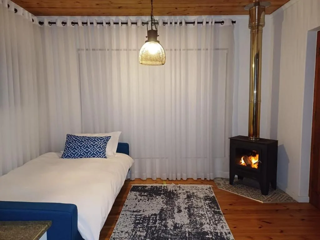 Bedroom with single bed, fireplace, pendant light, and sheer curtains