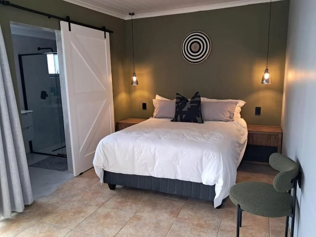 Spacious bedroom with queen bed, pendant lighting, and en-suite bathroom access