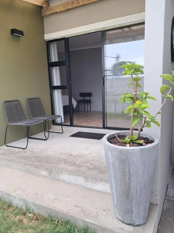 Outdoor patio with seating chairs and potted plants near sliding glass doors