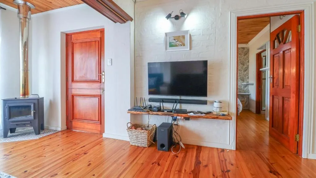 Spacious lounge with flat-screen TV, wooden flooring, and cosy fireplace