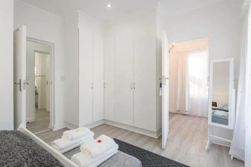 Bright modern bedroom with white built-in wardrobes and fresh towels