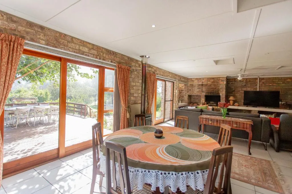 Dining area with wooden table and chairs, leading to deck and garden views